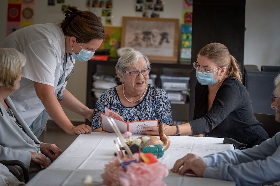 Photo illustrant une patiente entourée d'une professionnelle de santé et de ses proches